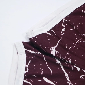 Detailed macro view of burgundy tie-dye fabric with white binding and double stitching