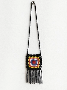 Detail of handmade crochet granny square bag with colorful floral pattern and black tassels