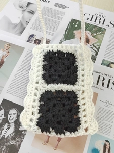 Detailed close-up of handmade crochet phone bag with black and white color block design