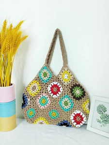 Detail of colorful handmade crochet grandmother square floral pattern on woven tote bag