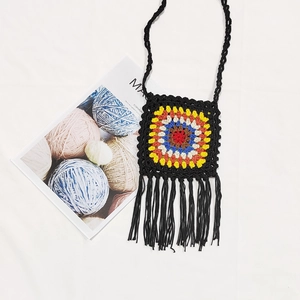 Detailed shot of a black handmade crochet crossbody bag with colorful granny square and long fringe