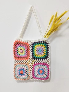 Detail of handmade crochet tote bag with colorful granny square patterns and white mesh weave