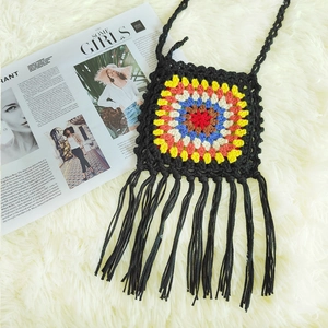 Detail of handmade crochet crossbody bag with colorful granny square and black tassels