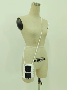 Detail of handmade crochet phone bag with black and white contrast knit pattern