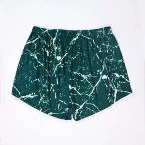 Detail view of dark green tie-dye beach shorts with elastic waist and white trim edges