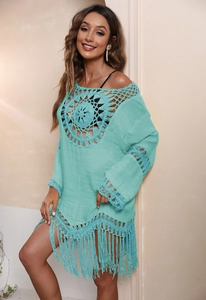 Details der Häkelstruktur und Blumenmuster auf türkisem Boho-Strandkleid mit Quasten
