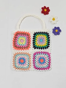 Close-up of handmade crochet tote bag with colorful granny square patterns on white yarn