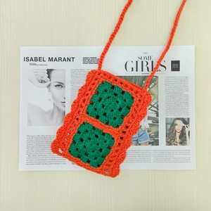 Detail shot of a handmade crochet mini bag with green and orange contrast squares
