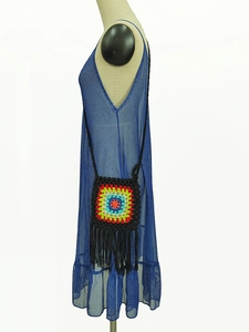 Detail of colorful hand-crocheted floral crossbody bag with long black decorative fringe