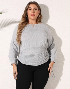 Detail of plus size long sleeve top featuring ruched waist design and light grey texture