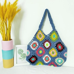 Detailed knit texture of a handmade blue bohemian crochet bag with granny square floral patterns