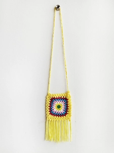 Close-up of handmade crochet granny square mini bag with vibrant colorful patterns and tassels