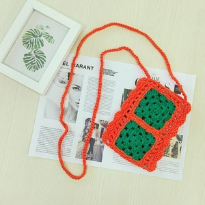 Detail of handmade crochet mini bag with vibrant orange yarn and green floral squares