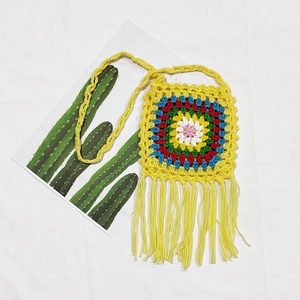 Detail of yellow handmade crochet crossbody bag with colorful mandala pattern and tassels
