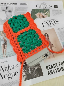 Detail view of handmade crochet phone bag with orange and green color contrast