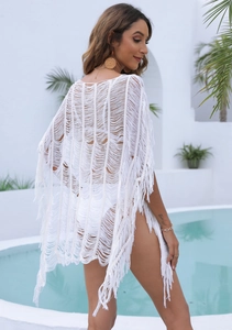 Detailed close-up of white bohemian crochet beach cover-up with intricate fringe and wave knit