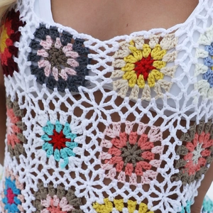 Close-up of handmade crochet top showing white floral hollow patterns and colorful tassels