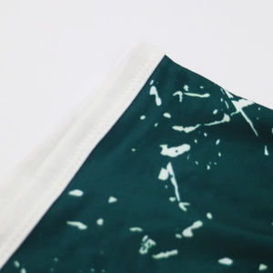 Detail showing the white stitching and marble print on these green beach shorts