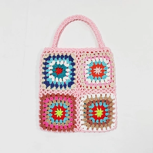 Handmade granny square crochet tote bag featuring colorful patchwork and pink woven handles