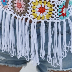 Detail of bohemian handmade crochet crop top with colorful floral squares and white tassels