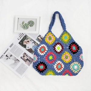 Handmade crochet tote bag with colorful granny square floral patterns in bohemian style