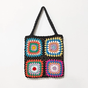 Close-up of handmade crochet tote bag with colorful granny square patterns on black yarn