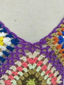 Macro detail of the multicolor crochet knit pattern and V-neckline texture on the top
