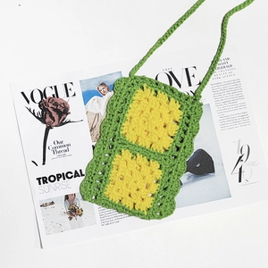 Close-up of handmade green knit bag with yellow granny square detail on a fashion magazine