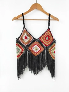 Close-up of handmade crochet granny square pattern with long black fringe tassels