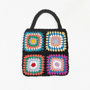 Detail of colorful hand-crocheted granny square patterns on a black bohemian tote bag