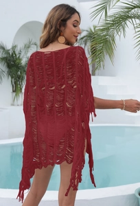 Detail of burgundy crochet beach cover-up featuring fringe hem and hollow knit texture