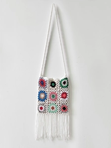 Detailed close-up of handmade granny square crochet bag with colorful floral patterns and tassels
