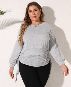Close-up of drawstring waist detailing and pleated fabric on the grey long sleeve sweatshirt