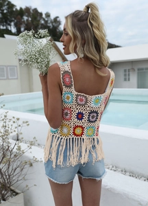 Close-up of handmade crochet vest featuring colorful floral patterns and long fringe