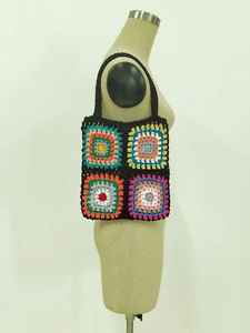 Detail of colorful granny square crochet tote bag with vivid knit texture and black straps