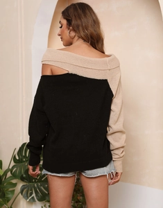 Dettaglio del maglione in maglia con spalle scoperte e design color-block asimmetrico