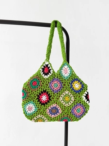 Detail of handmade crochet granny square tote bag with colorful floral patterns and green trim