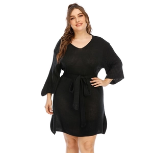 Detail of plus size black knit dress featuring a V-neck and flared sleeves with waist tie