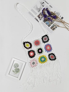 Detail of colorful granny square crochet bag with white fringe and bohemian floral pattern