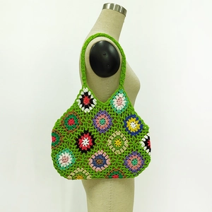 Detailed macro view of granny square crochet texture and colorful floral patterns on a bag