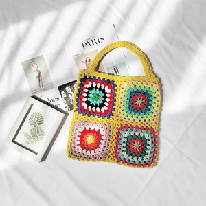 Handmade crochet granny square tote bag with colorful patchwork on white fabric background