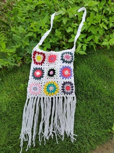 Detailed close-up of white bohemian crochet crossbody bag with colorful granny square patterns