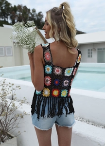Detail of bohemian crochet vest featuring colorful floral patterns and black fringe hem