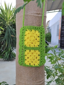 Close-up of handmade green crochet bag with yellow flower granny square pattern