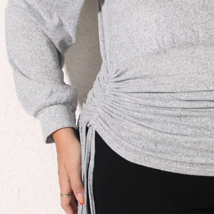 Detail of ruched side with adjustable drawstring on heathered grey long sleeve sweatshirt