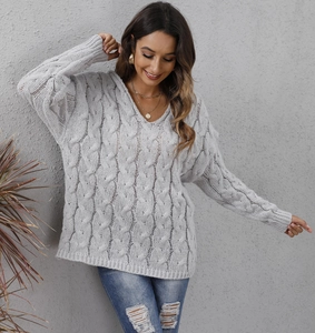 Close-up of thick light gray cable knit texture on a loose V-neck hooded sweater