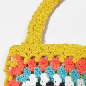 Close-up of colorful handmade crochet tote bag showing detailed knit texture and yellow handle