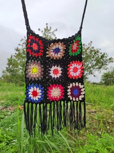 Detailed view of colorful handmade crochet grandmother square bag with long black fringe