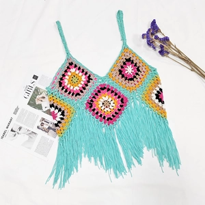 Close-up of handmade crochet crop top with colorful floral patterns and long fringe details