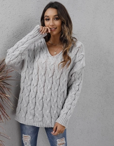 Detail showing grey cable knit texture and V-neckline of a chunky oversized sweater